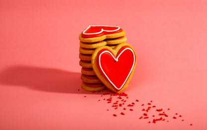 12 biscuits en forme de coeur avec glaçage royal rouge et contour blanc.
